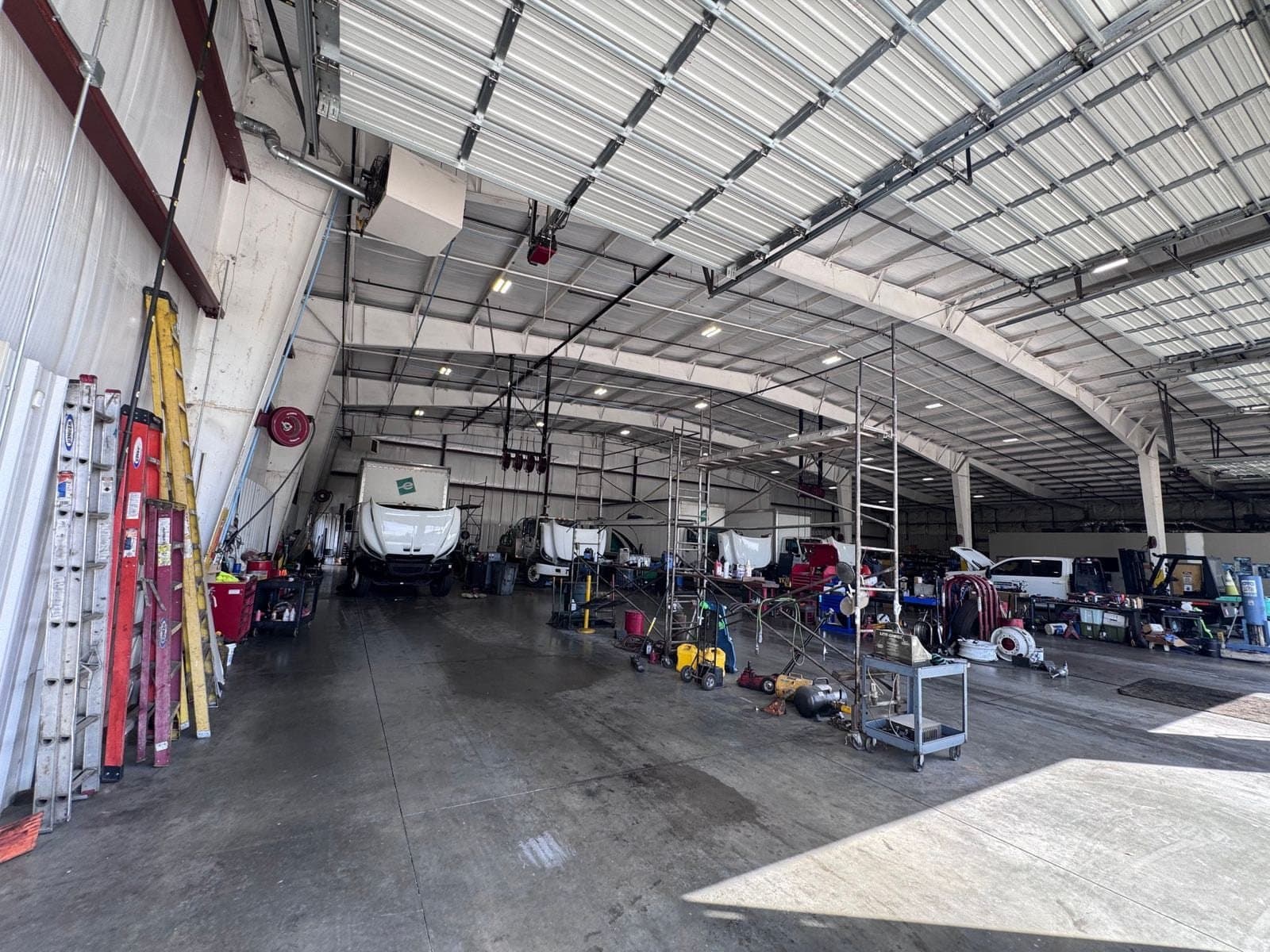 Inside the Diesel Doctors shop, a wide bay with trucks and equipment under a steel roof